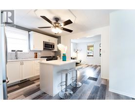A kitchen with white cabinets and a white island with bar stools.