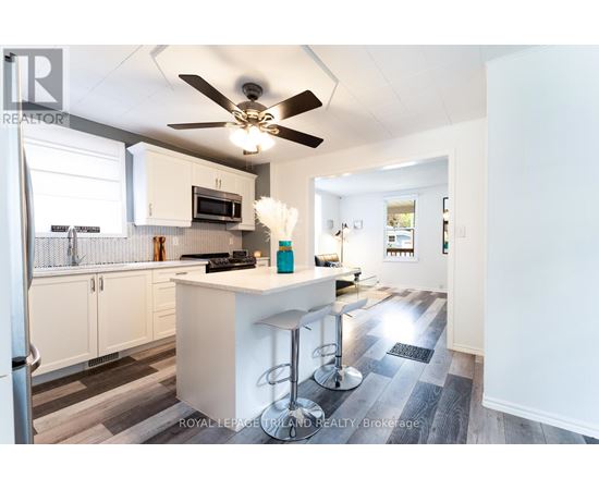A kitchen with white cabinets and a white island with bar stools.