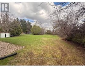A backyard with a grassy area, a tree, and a white fence.