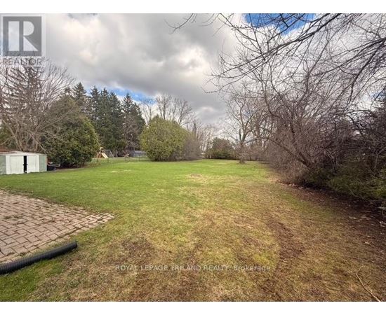 A backyard with a grassy area, a tree, and a white fence.