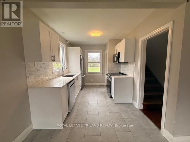 A kitchen with white cabinets and a tiled floor.