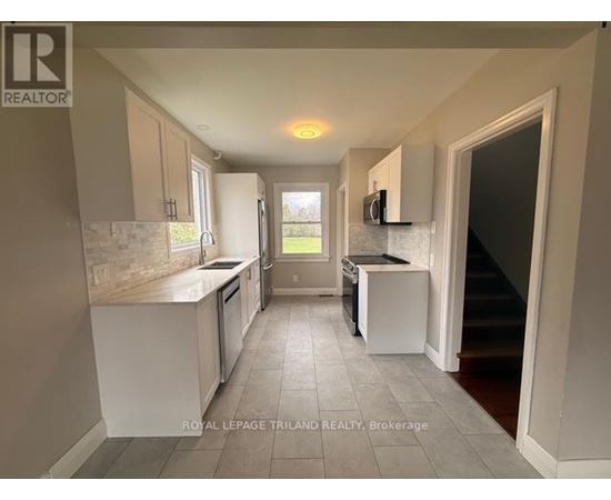 A kitchen with white cabinets and a tiled floor.