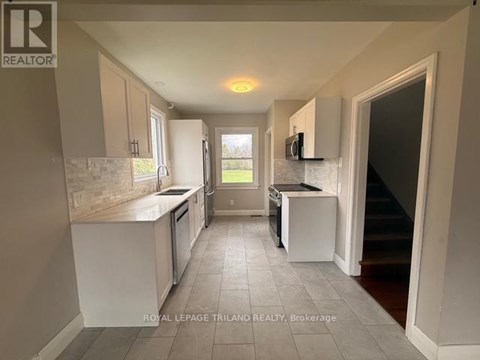 A kitchen with white cabinets and a tiled floor.