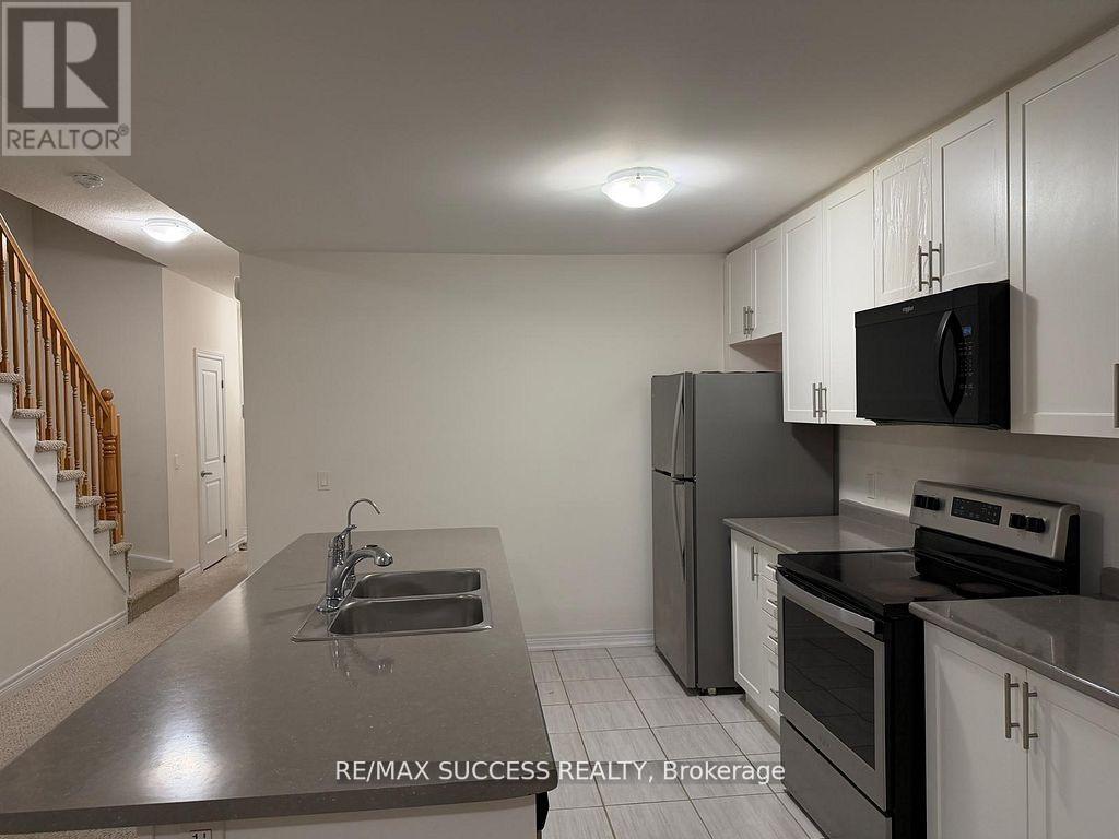 A kitchen with a refrigerator, oven, and sink.