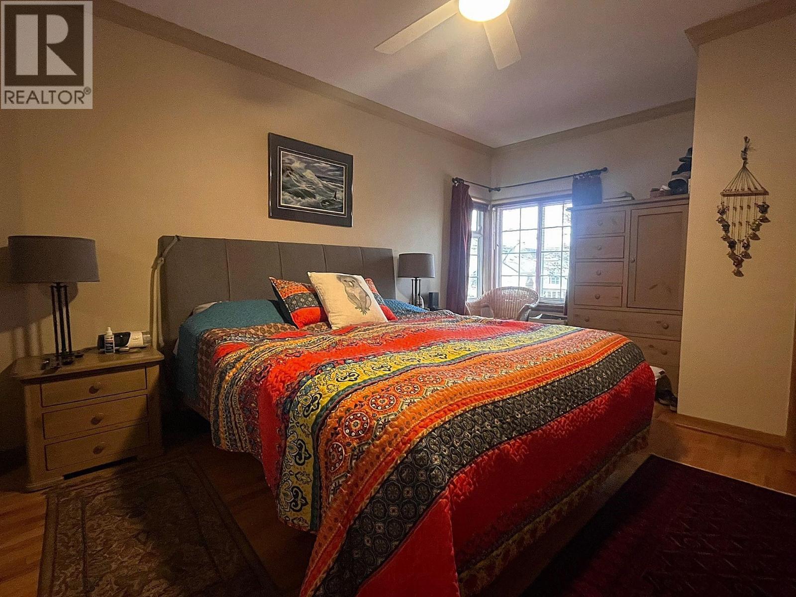 A bedroom with a bed covered in a multicolored quilt.