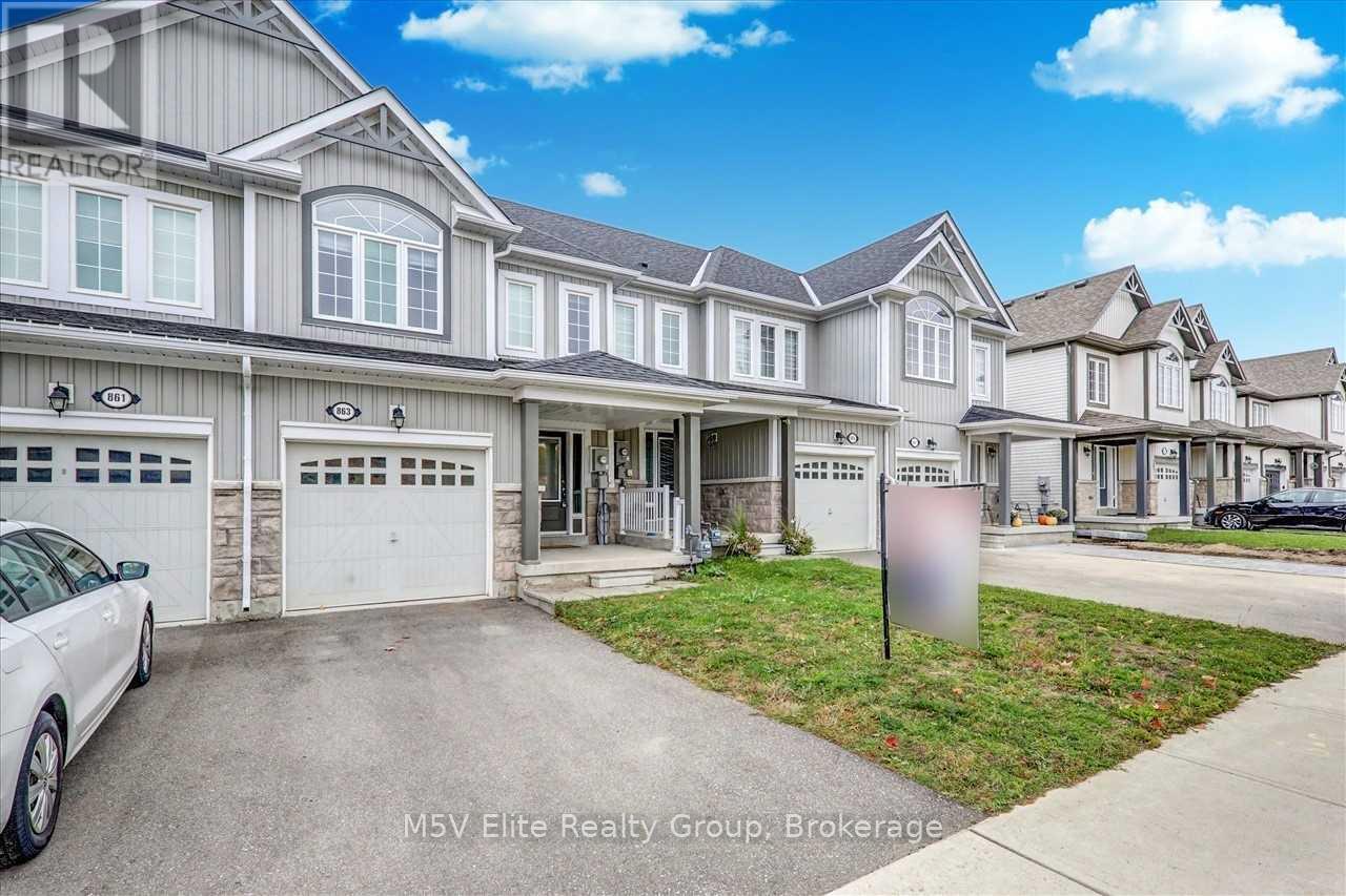 A white car is parked in front of a house with a sign that reads "M5V Elite Realty Group, Brokerage".