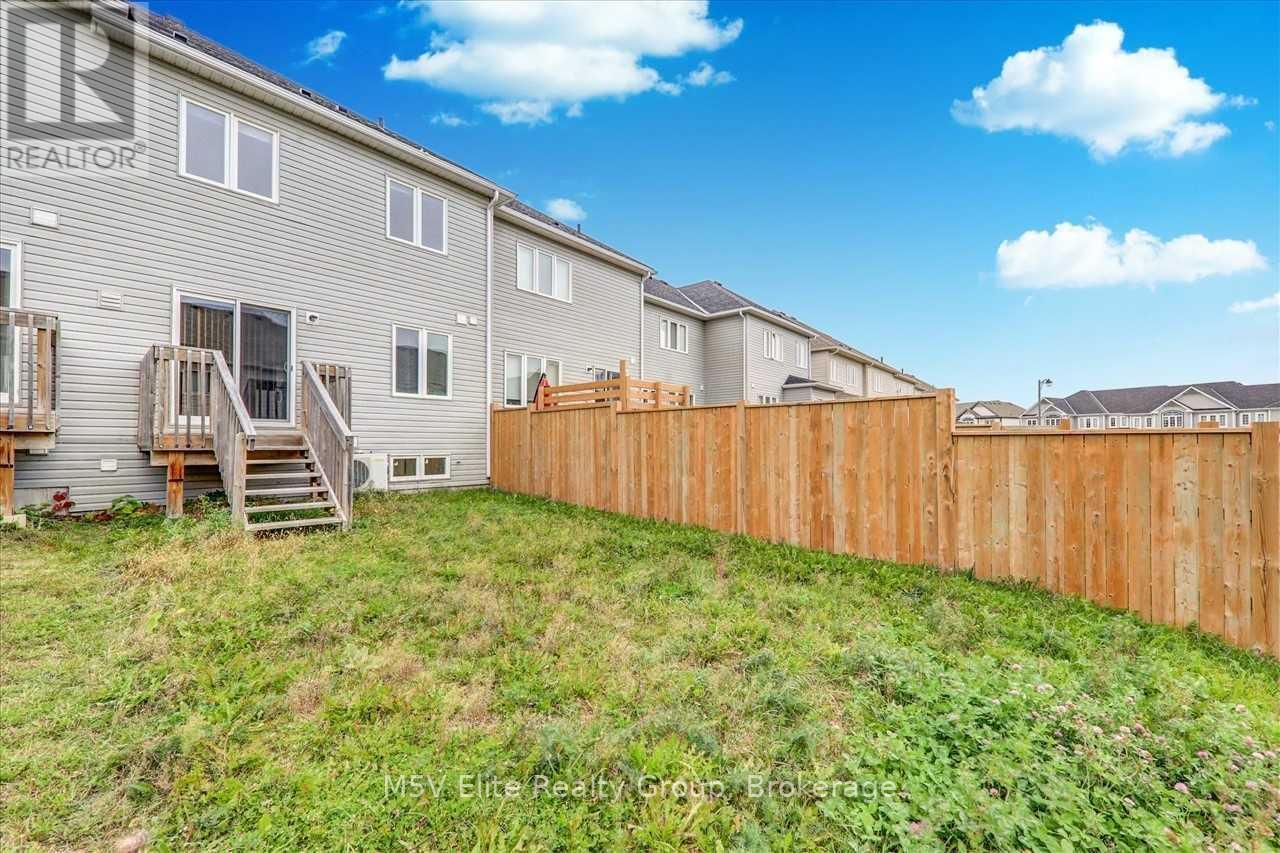 A grassy area in front of a grey building with a wooden fence.