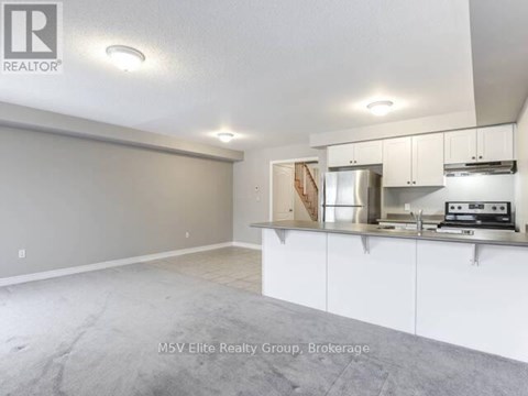 A real estate listing image of a kitchen with white cabinets and a stainless steel counter.