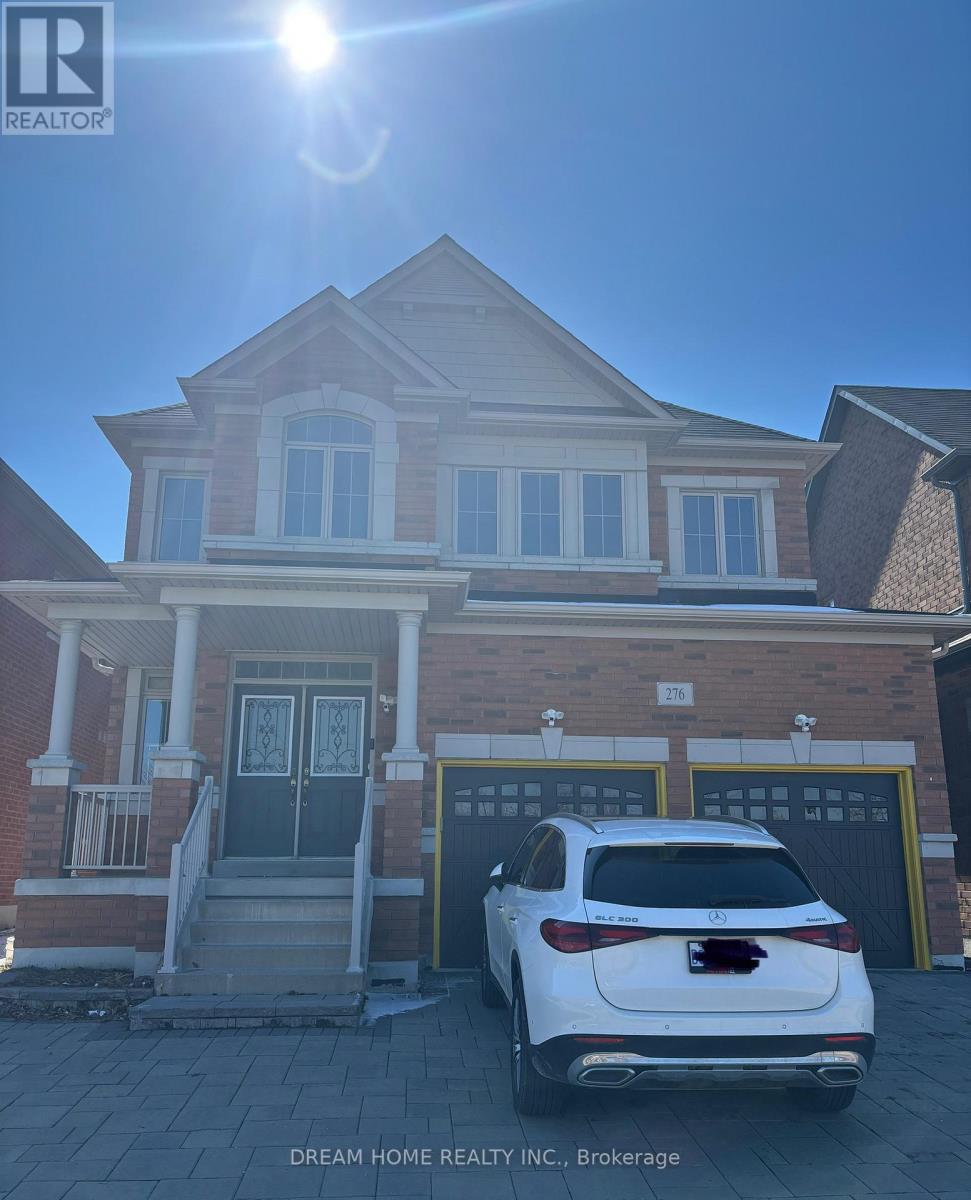 A white car is parked in front of a house with a garage.