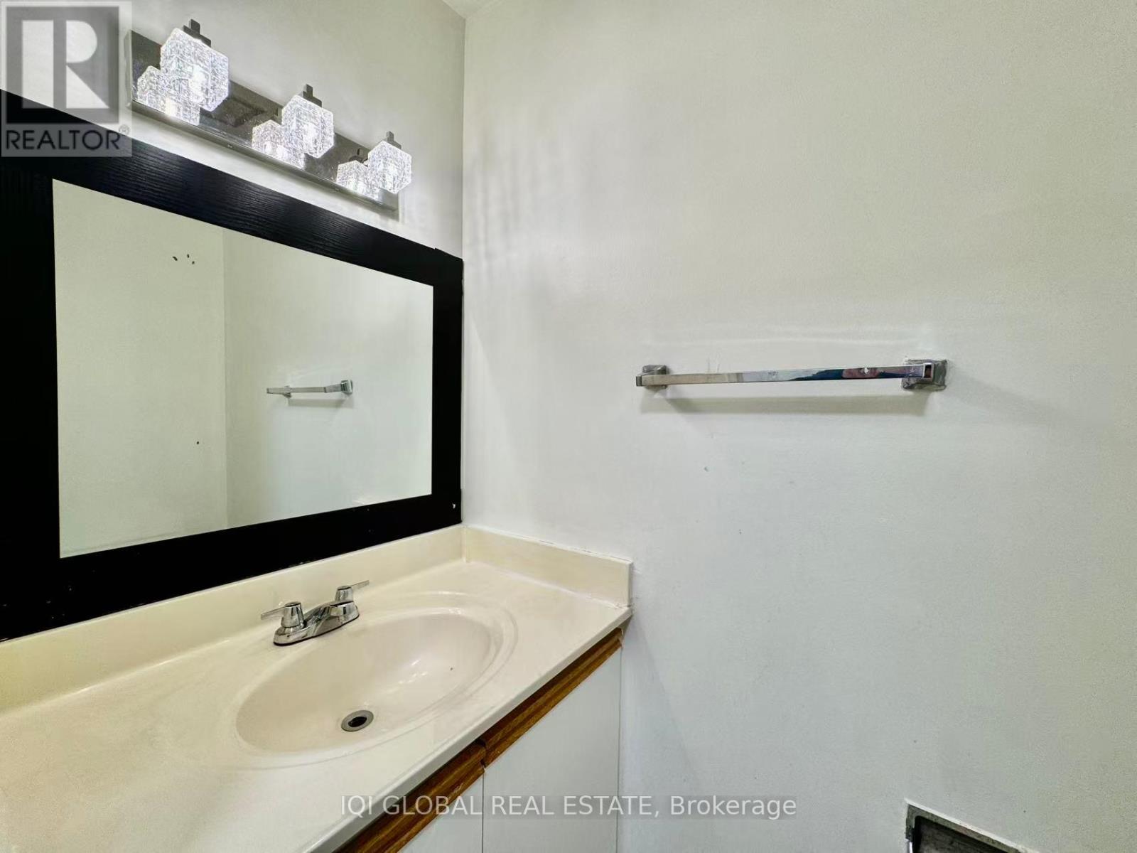 A bathroom with a sink, mirror, and towel bar.