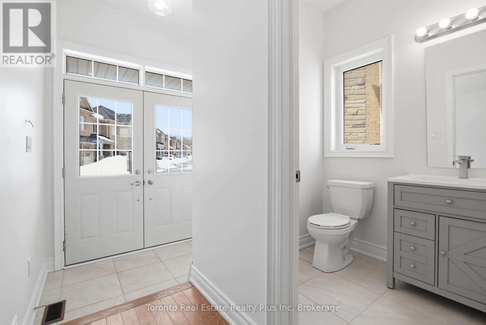 A bathroom with a toilet, sink, and a view of a building outside the window.