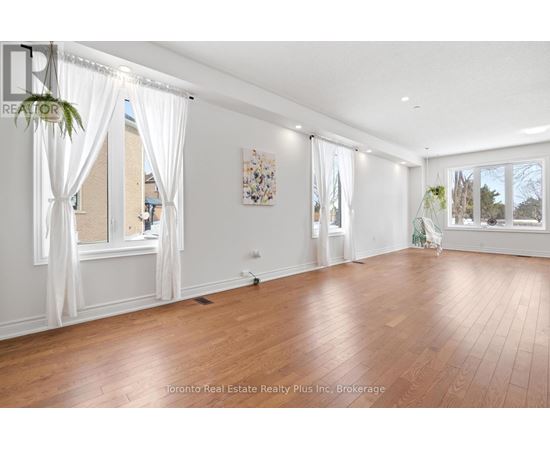 A spacious room with wooden floors and white curtains.