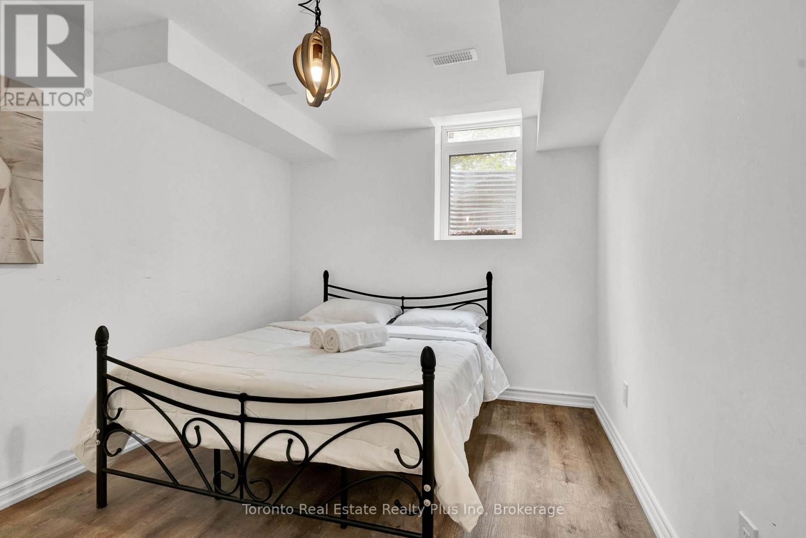 A bedroom with a black metal bed frame and a small window.