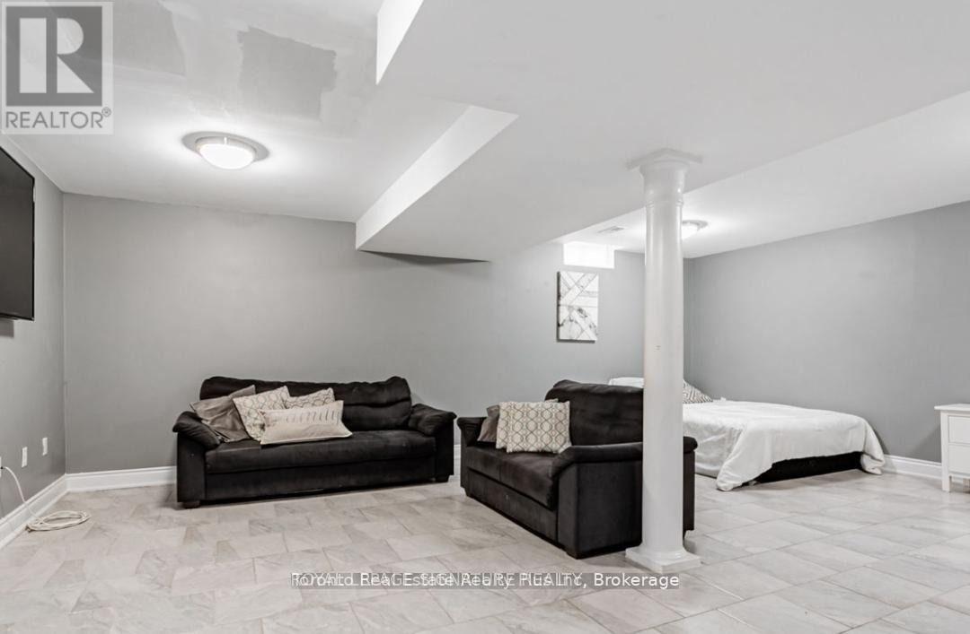 A living room with a black couch and a white bed.