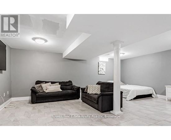 A living room with a black couch and a white bed.