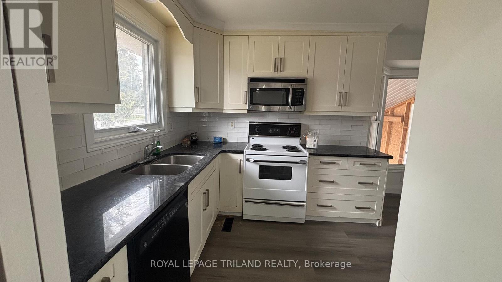 A kitchen with a black countertop and white cabinets.