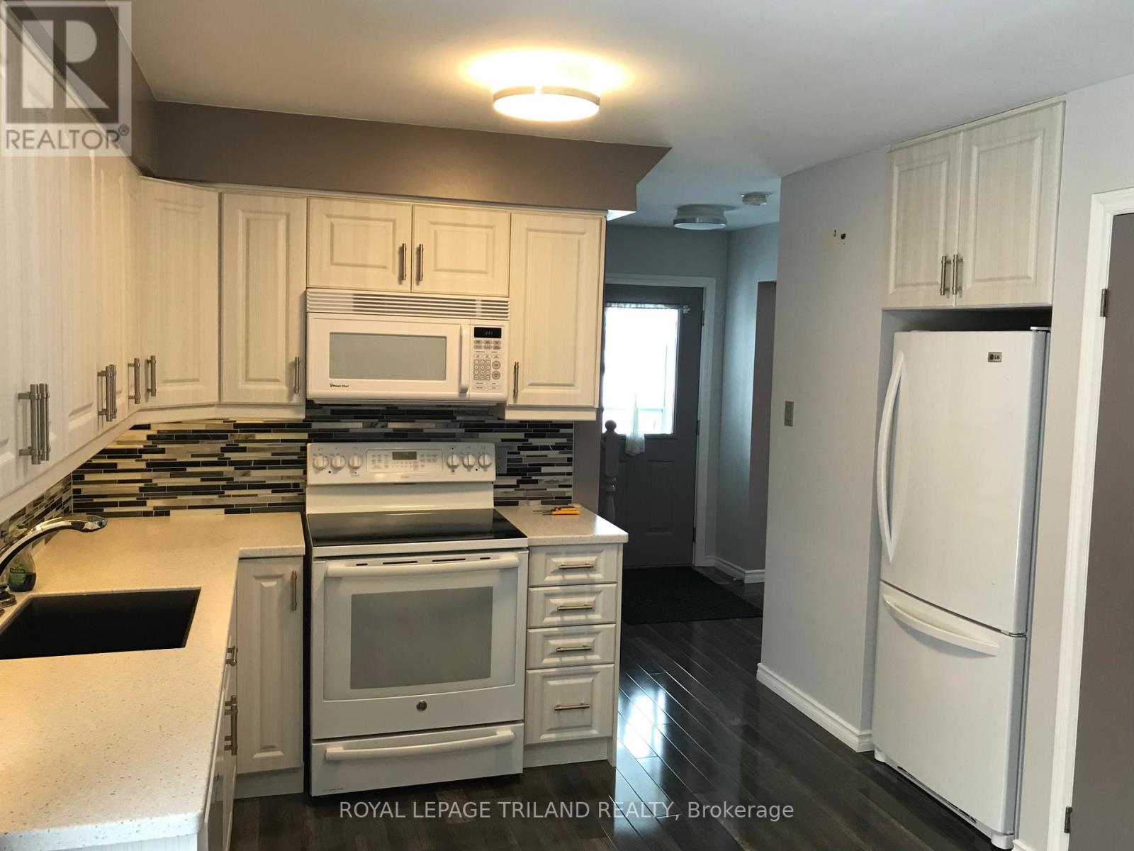 A kitchen with white cabinets and appliances.