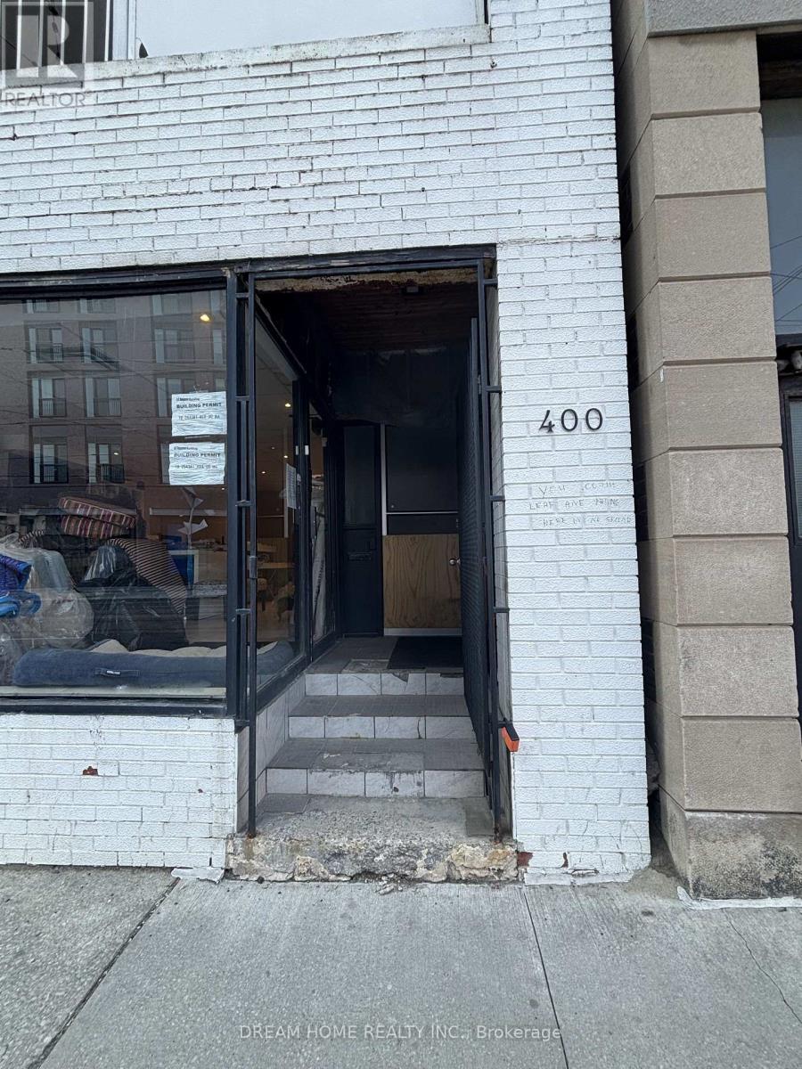A white building with a black door and a sign that says "Dream Home Realty Inc: Brokerage".