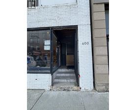 A white building with a black door and a sign that says "Dream Home Realty Inc: Brokerage".