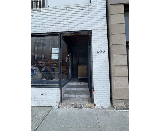 A white building with a black door and a sign that says "Dream Home Realty Inc: Brokerage".