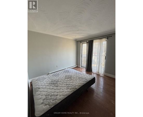 A bedroom with a large bed and a window with curtains.