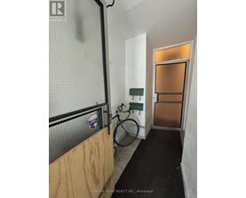 A bicycle is leaning against a wall in a room with a door.