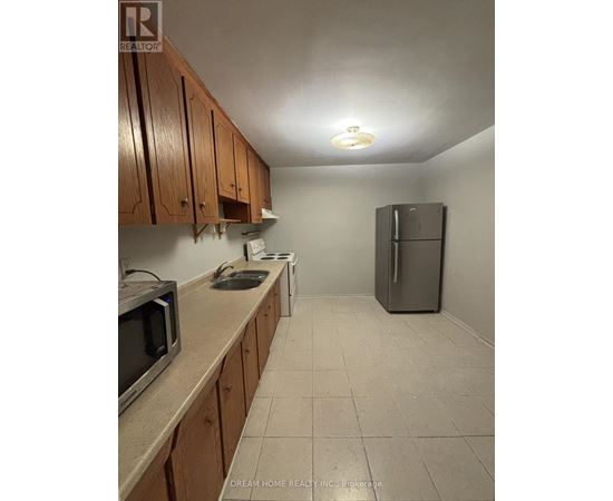 A kitchen with wooden cabinets and a refrigerator.