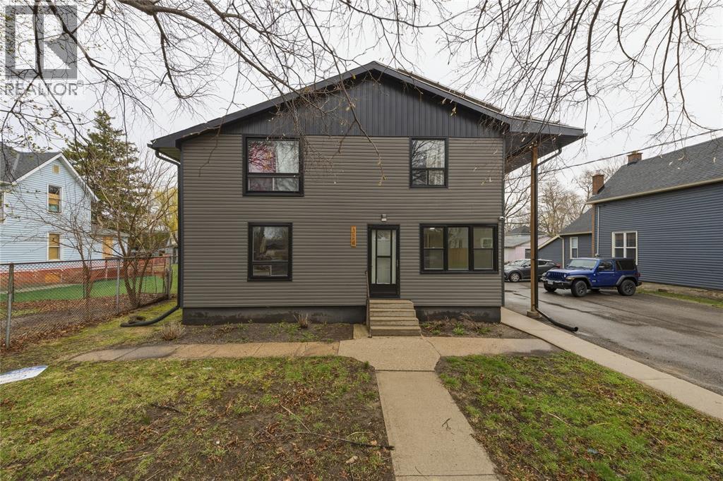 A grey house with a black roof and a small front yard.