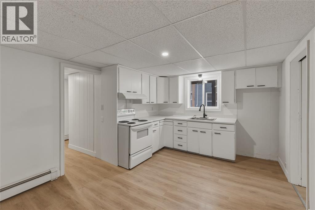 A white kitchen with wooden floors and white cabinets.