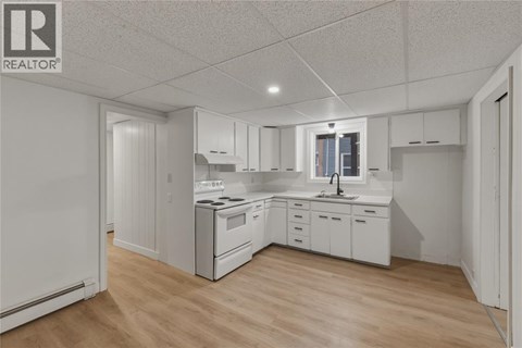 A white kitchen with wooden floors and white cabinets.