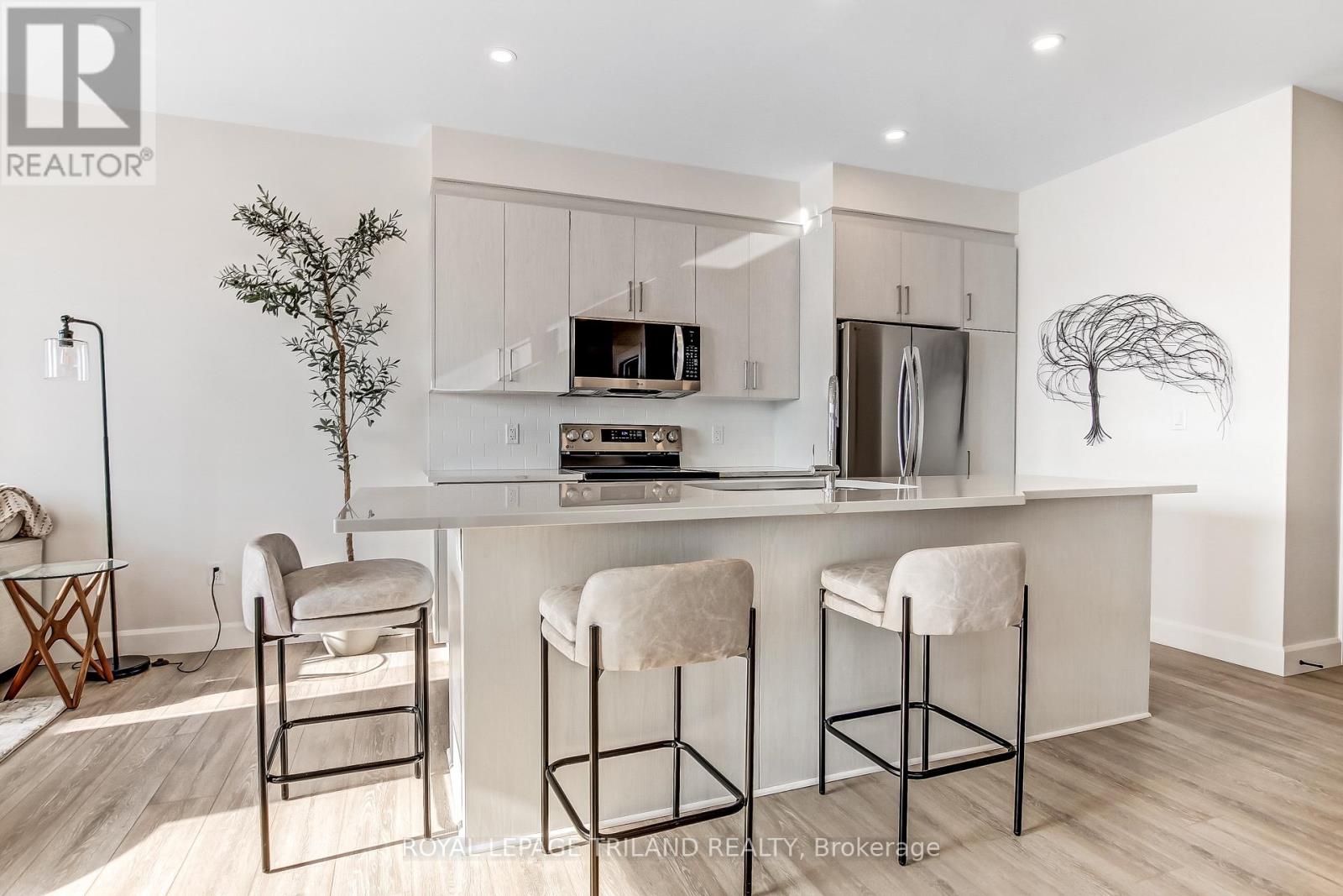 A modern kitchen with white cabinets and a white island with bar stools.