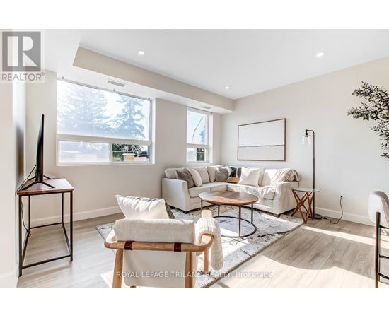 A living room with a white sofa set, a wooden coffee table, and a large window.