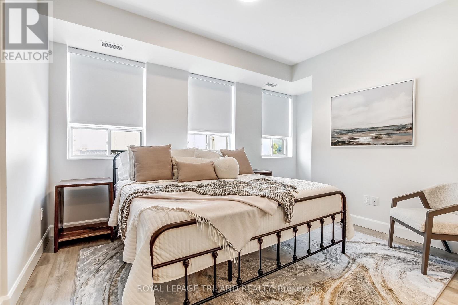 A bedroom with a bed, chair, and a painting on the wall.