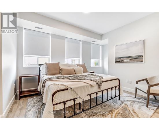 A bedroom with a bed, chair, and a painting on the wall.