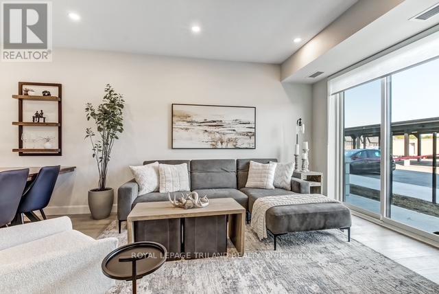 A living room with a grey couch and a large painting on the wall.