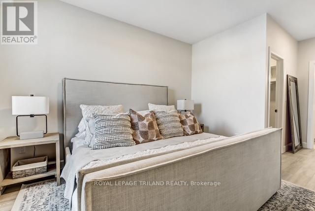 A bedroom with a large bed and a nightstand with a lamp.
