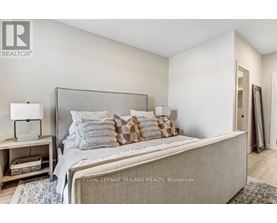 A bedroom with a large bed and a nightstand with a lamp.