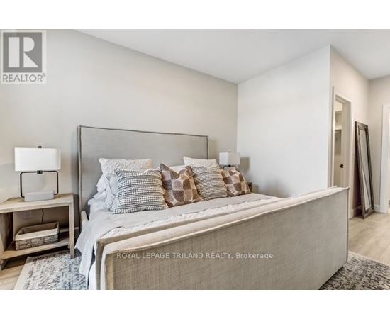A bedroom with a large bed and a nightstand with a lamp.