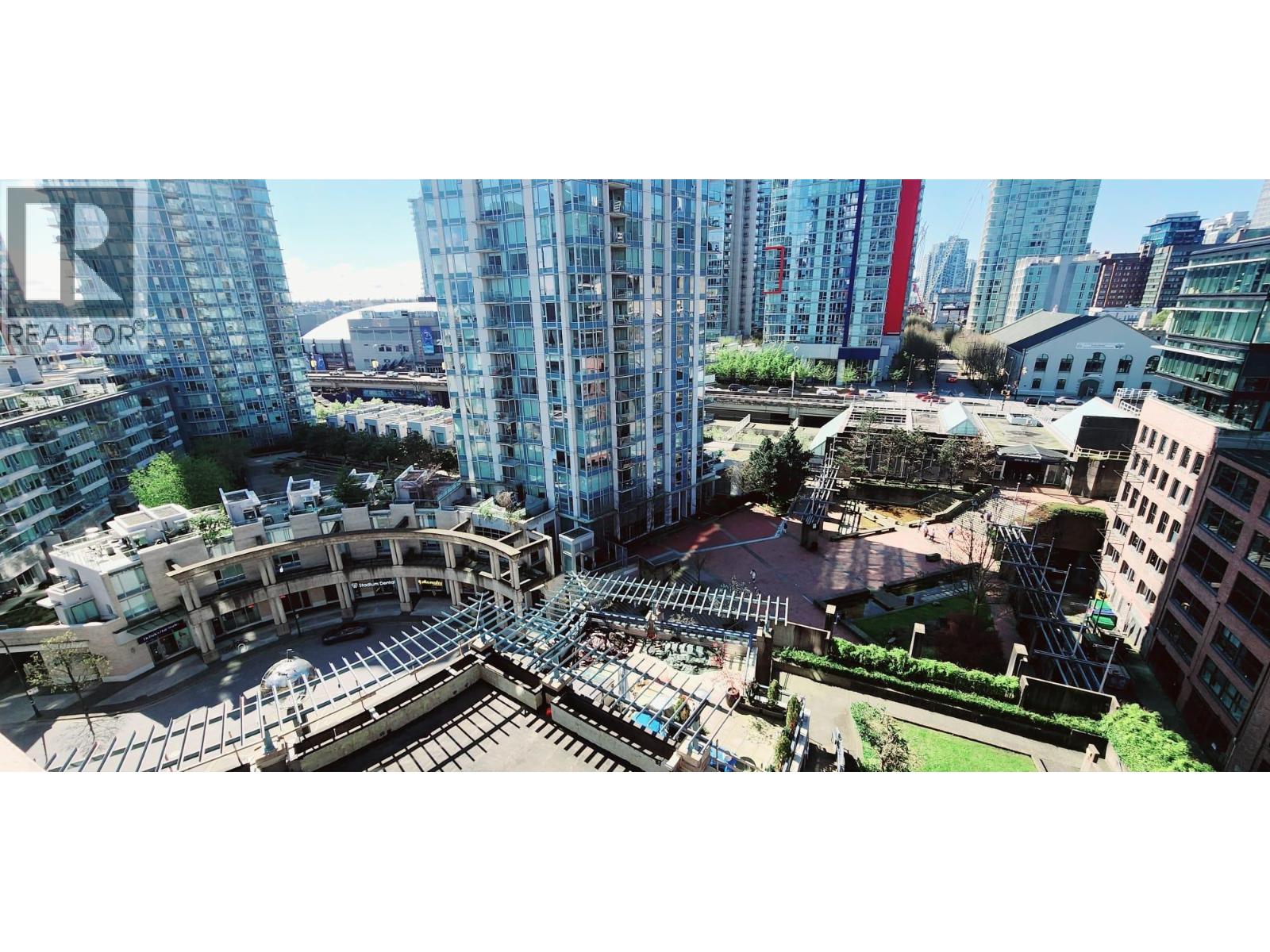 A cityscape with a mix of modern and older buildings, featuring a large open space in the foreground.