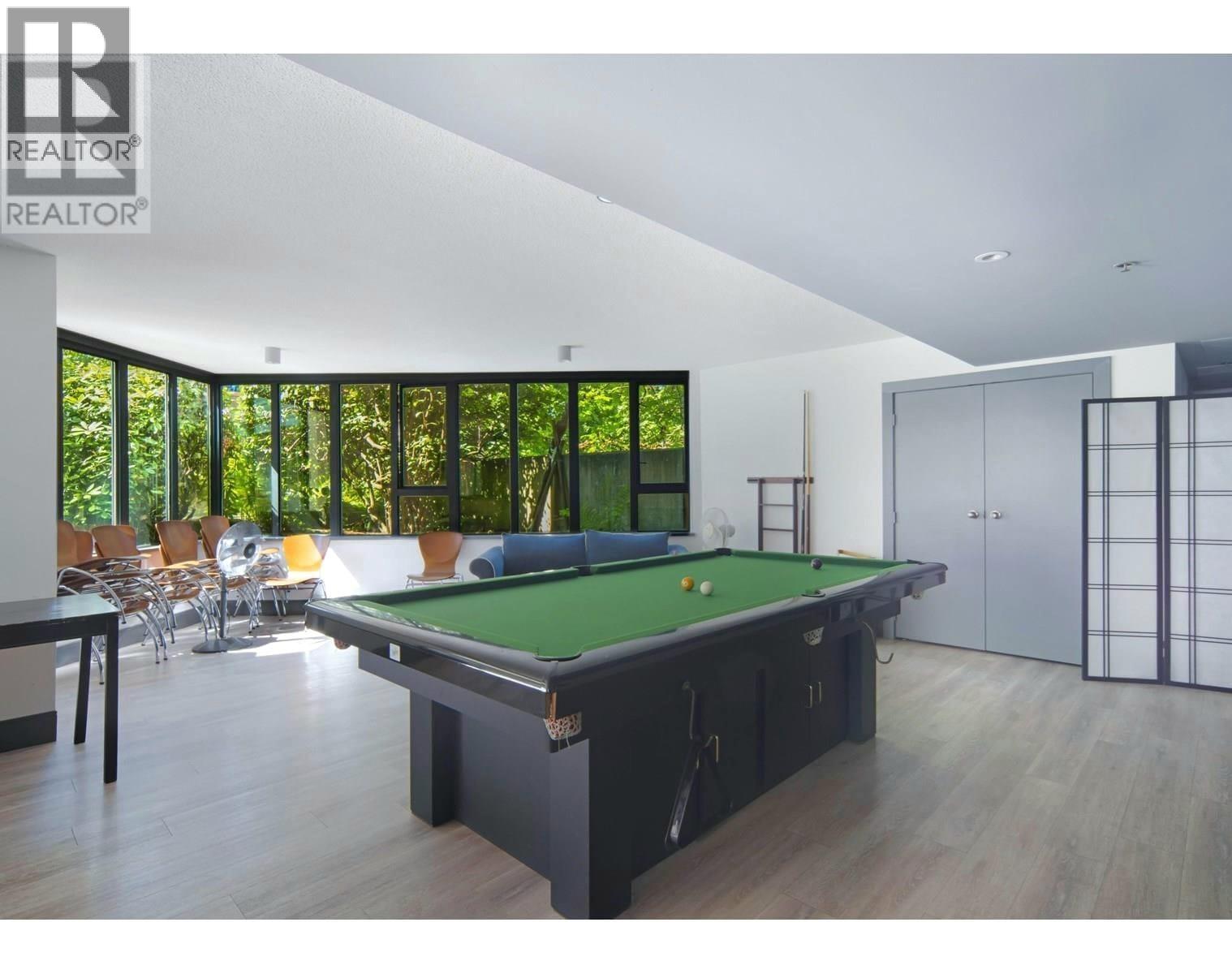 A billiard table is in the middle of a room with a pool table chair and a pool table.