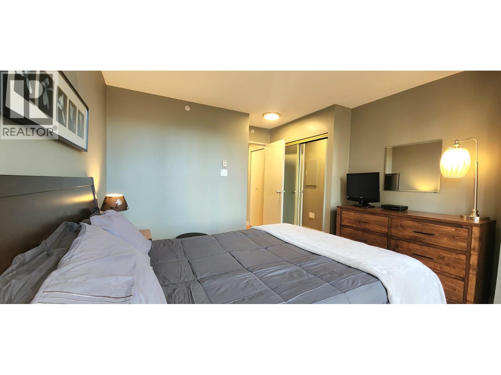 A bedroom with a bed, nightstand, and a dresser with a mirror.