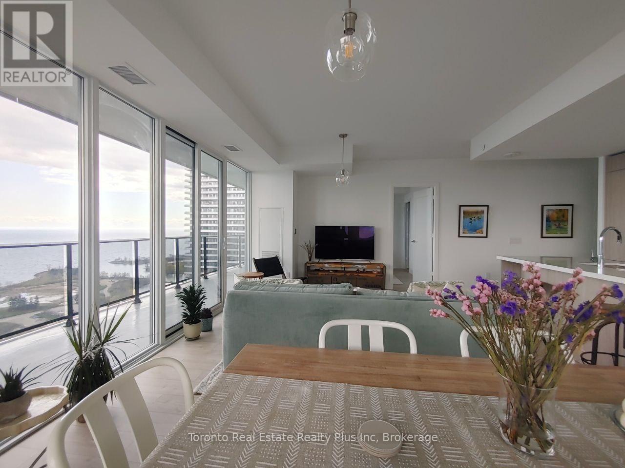 A dining room with a table and chairs and a television in the background.