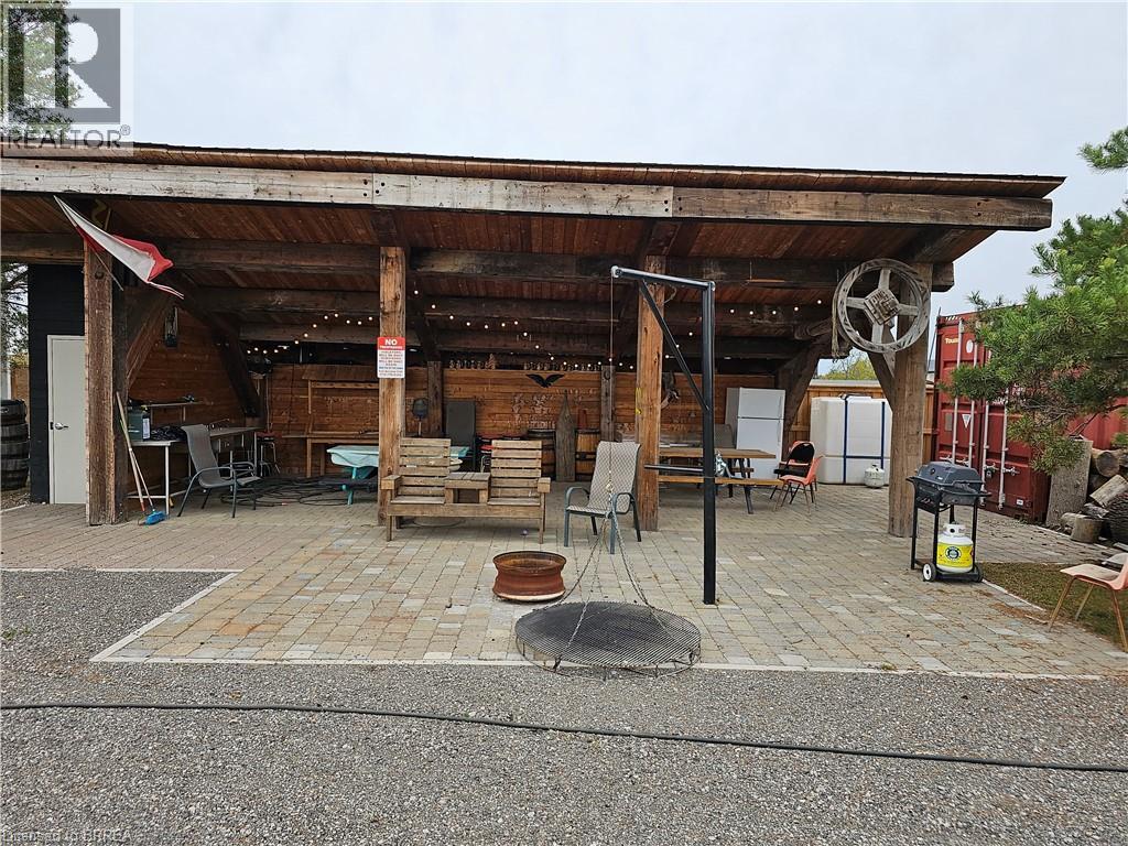 A wooden structure with a wheel on top and a fire pit in the middle of a brick patio.