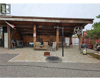 A wooden structure with a wheel on top and a fire pit in the middle of a brick patio.