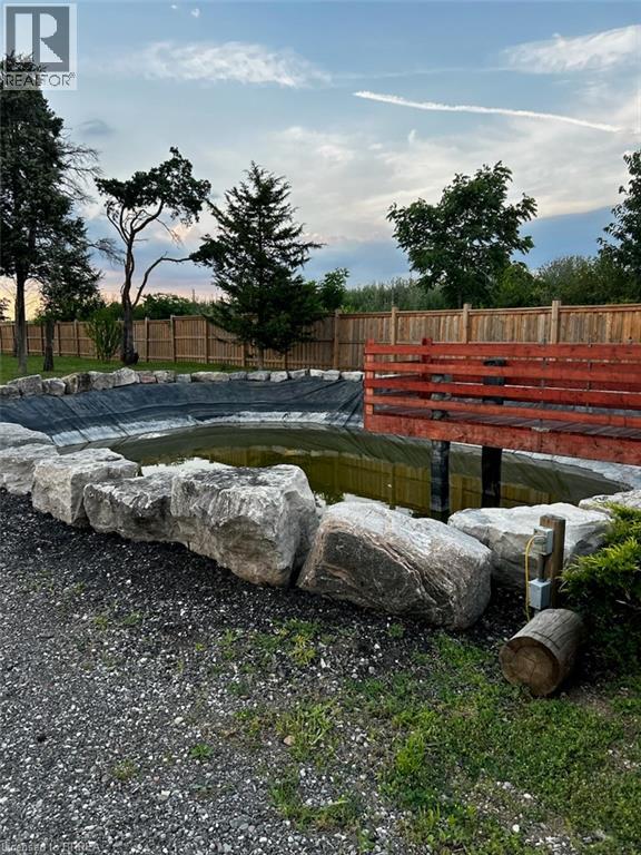 A small pond surrounded by rocks and a wooden fence.