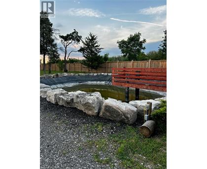 A small pond surrounded by rocks and a wooden fence.