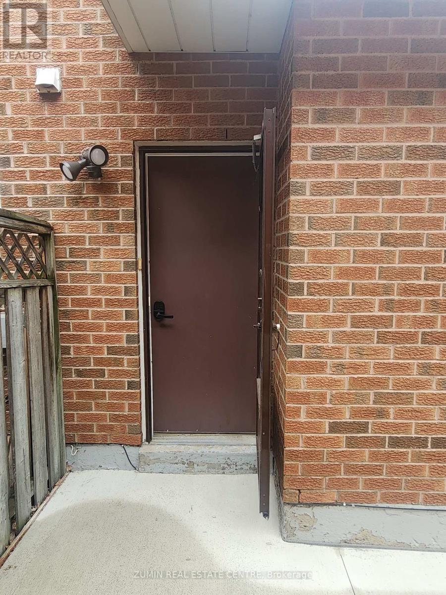 A brown door is at the end of a brick wall.
