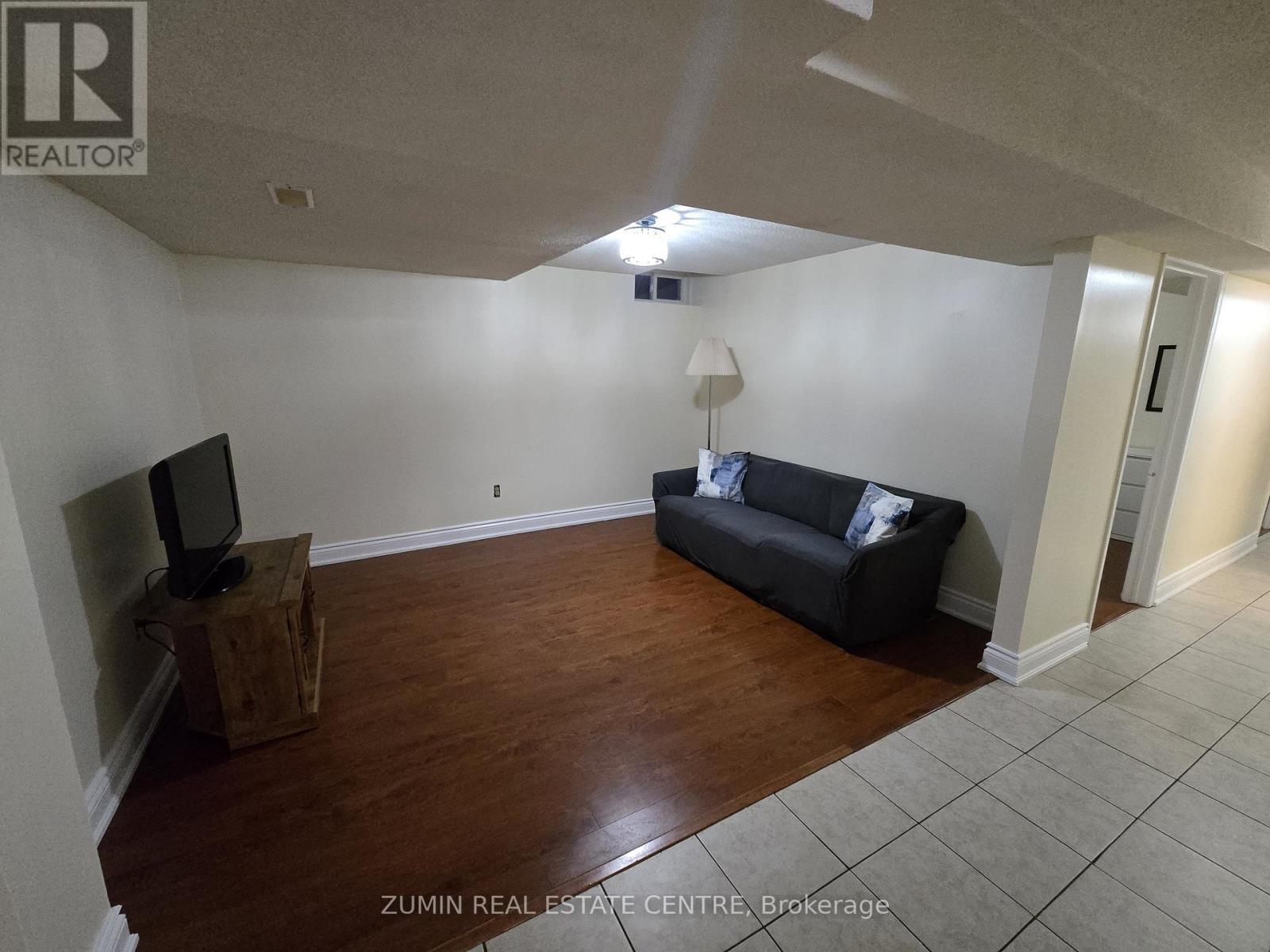 A living room with a black couch and a television on a wooden stand.