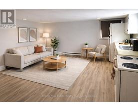 A well-lit, modern living room with a kitchen area in the background.