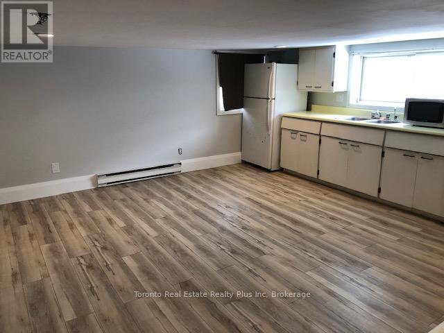 A kitchen with white cabinets and a wooden floor.